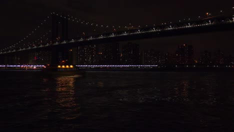 the brooklyn bridge by night with the new york city skyline in the background and subway passing