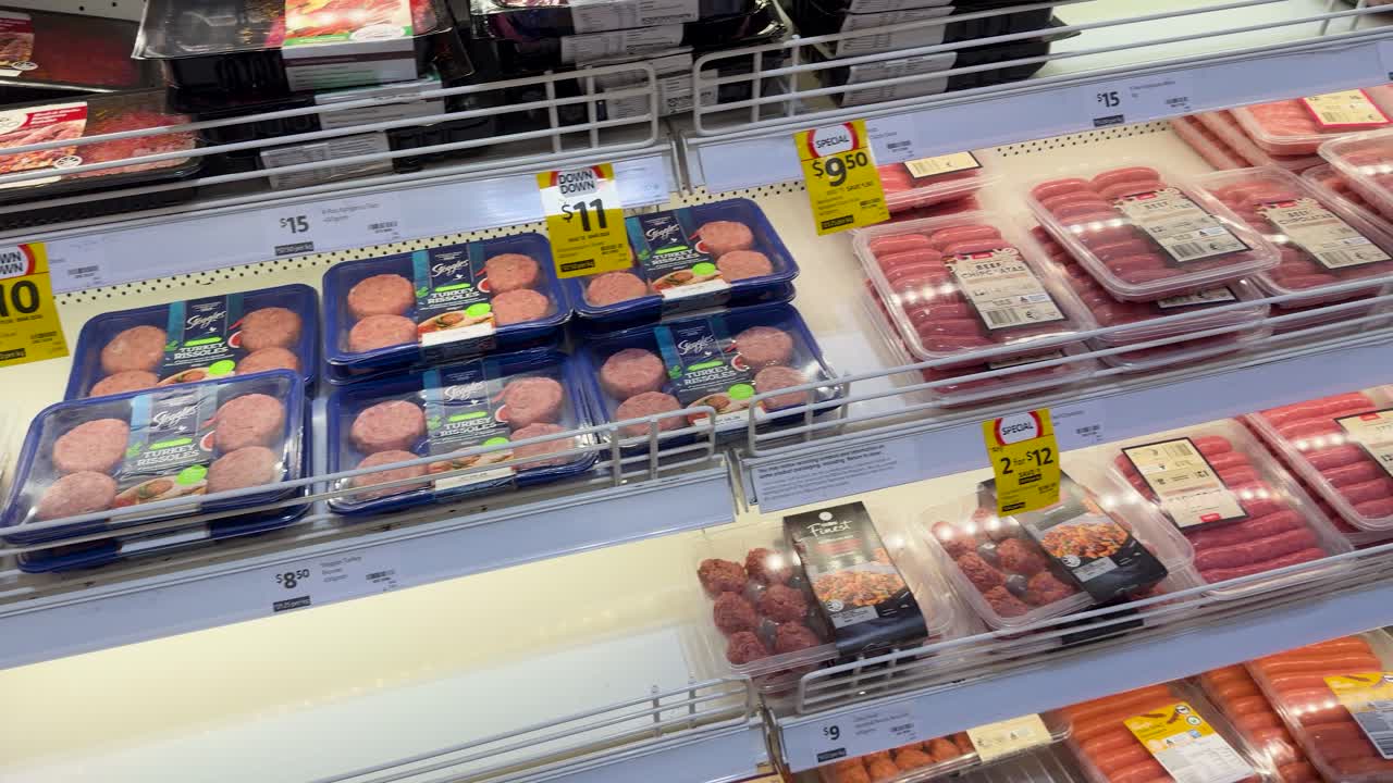 Una lenta panoramica attraverso scaffali refrigerati riforniti di prodotti confezionati a base di pollame e manzo.
