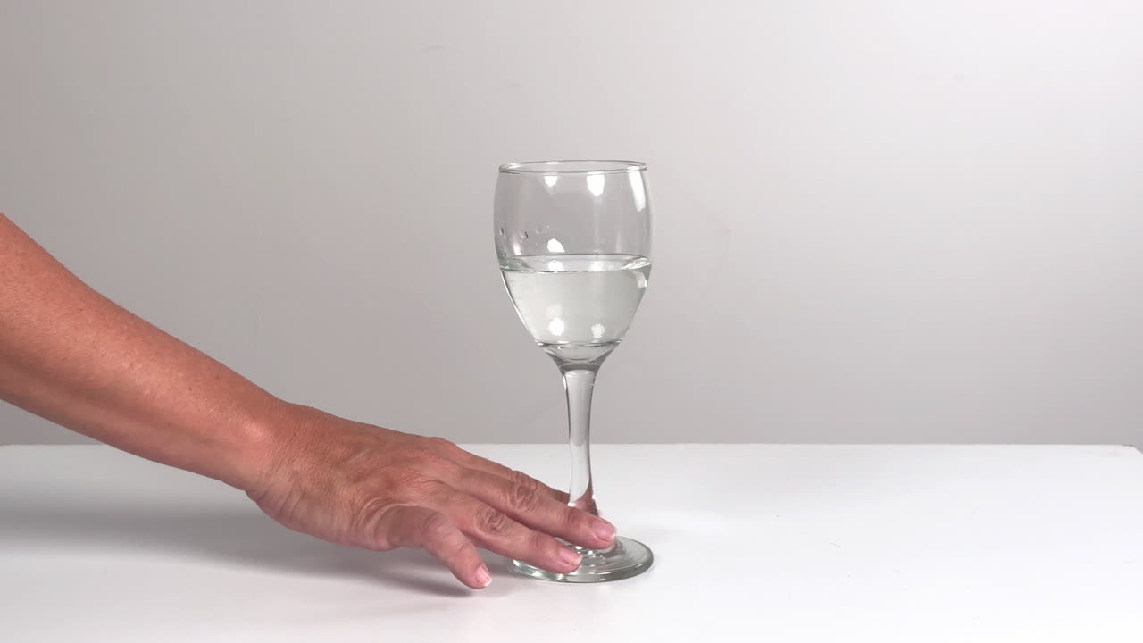 Nærbilde av hånd som gnir vinglass med vann