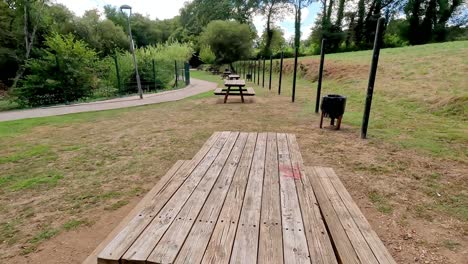 Lonely-wooden-tables-in-public-park-with-trash-cans-and-streetlights,-no-people-on-a-sunny-summer-day,-shot-from-bottom-up,-Ordes,-Galicia,-Spain