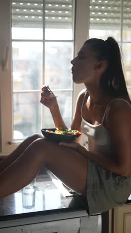 woman eating salad by the window