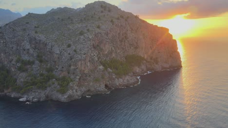 tiro de dron hacia abajo de la montaña con puesta de sol en el fondo sobre el mar mediterráneo en sa calobra, mallorca, españa