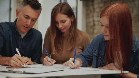 Coworkers-working-together-in-the-office.-Women-and-men-writing-and-taking-notes-for-a-new-company-project.