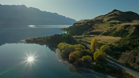 carretera rural a lo largo de la orilla del lago de nueva zelanda con un brillante reflejo de la luz solar