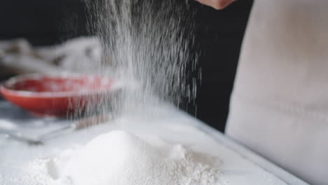 close up of hands of female baker sifting flour