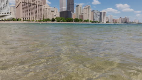 imágenes estáticas de las aguas del lago michigan que se despliegan para revelar el rascacielos 875 north michigan avenue y el centro de chicago.