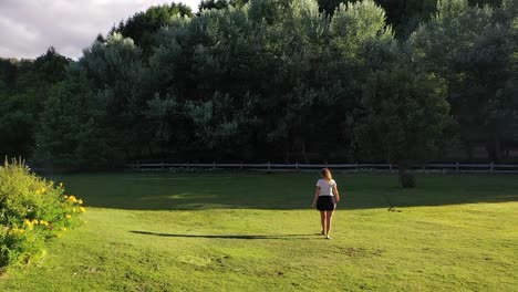 Following-back-young-Female-walking-in-a-big-house-garden-at-sunset-aerial-recorded-in-Slow-Motion-60fps