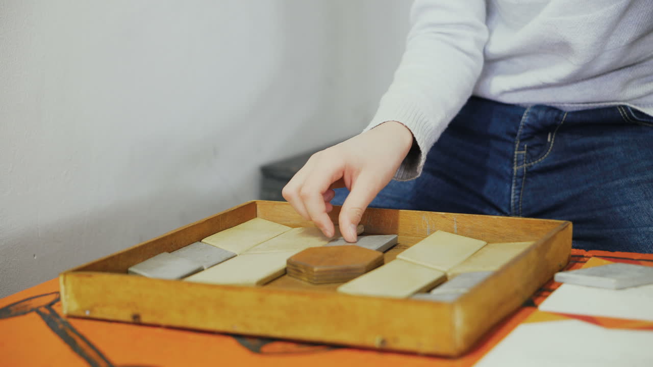 Close-up, hands of a child playing with wooden bricks on a table. Boy with a wooden puzzle. Concept of education.