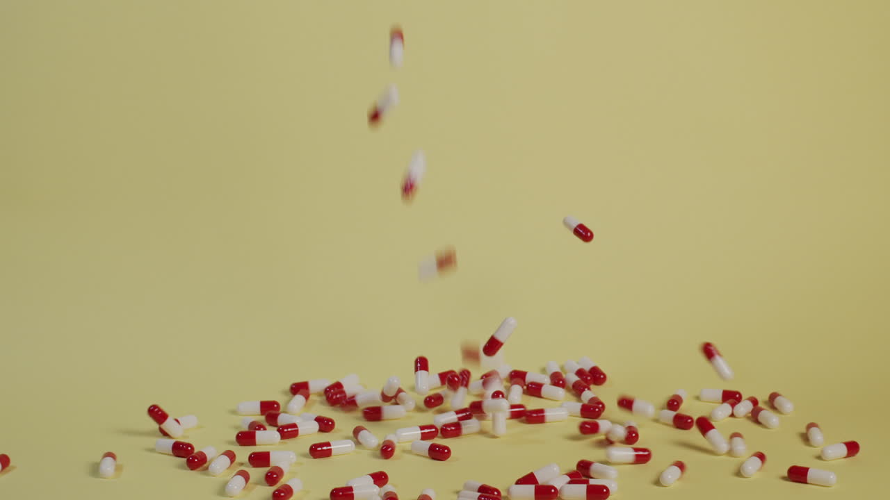 한 줌의 알약이 수직으로 떨어지고 주위를 튕기면서 슬로우 모션 와이드 샷