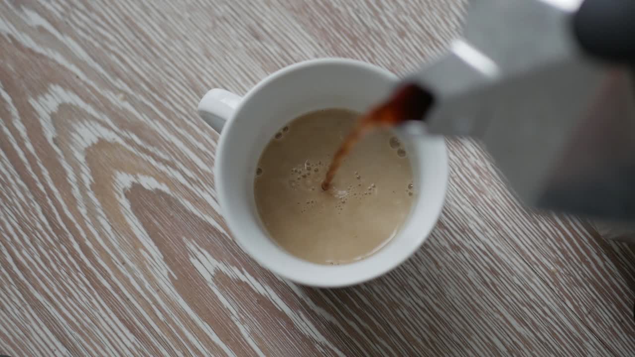 비알레티 모카 익스프레스의 뜨거운 커피를 우유와 함께 작은 컵에 붓는다