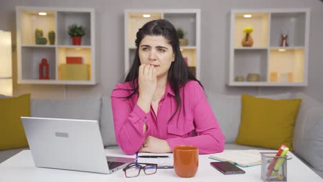 home office worker woman biting her nails looking at camera.