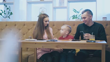 small-child-sits-between-handsome-man-and-nice-lady-on-sofa