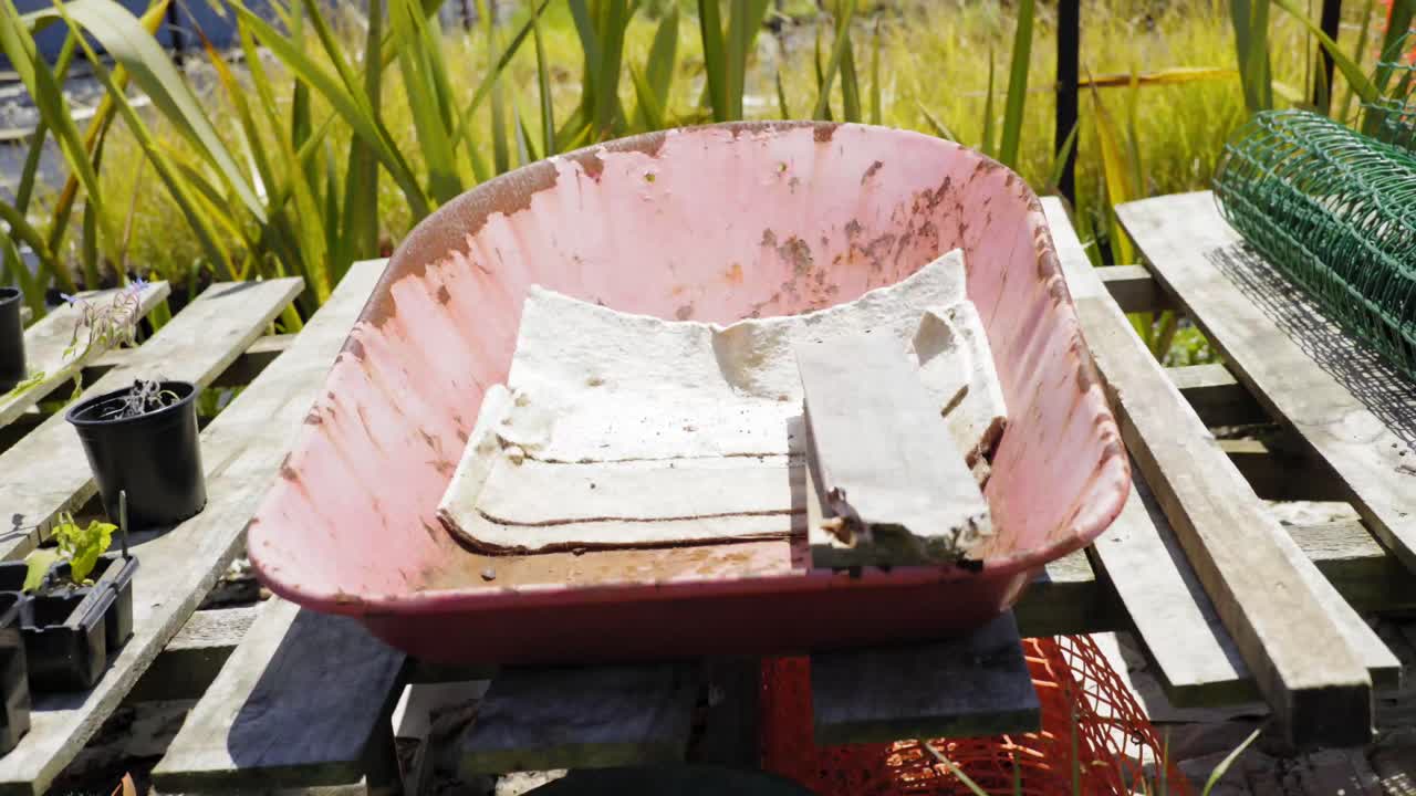 농지 정원에서 빈 녹슨 트롤리로 패닝하는 냄비에 있는 식물