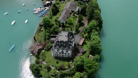 flying over castle seeburg revealing the castle and its nature view at the turquoise lake brienzersee near interlaken in iseltwald switzerland surrounded by a beutiful green nature, alp mountains