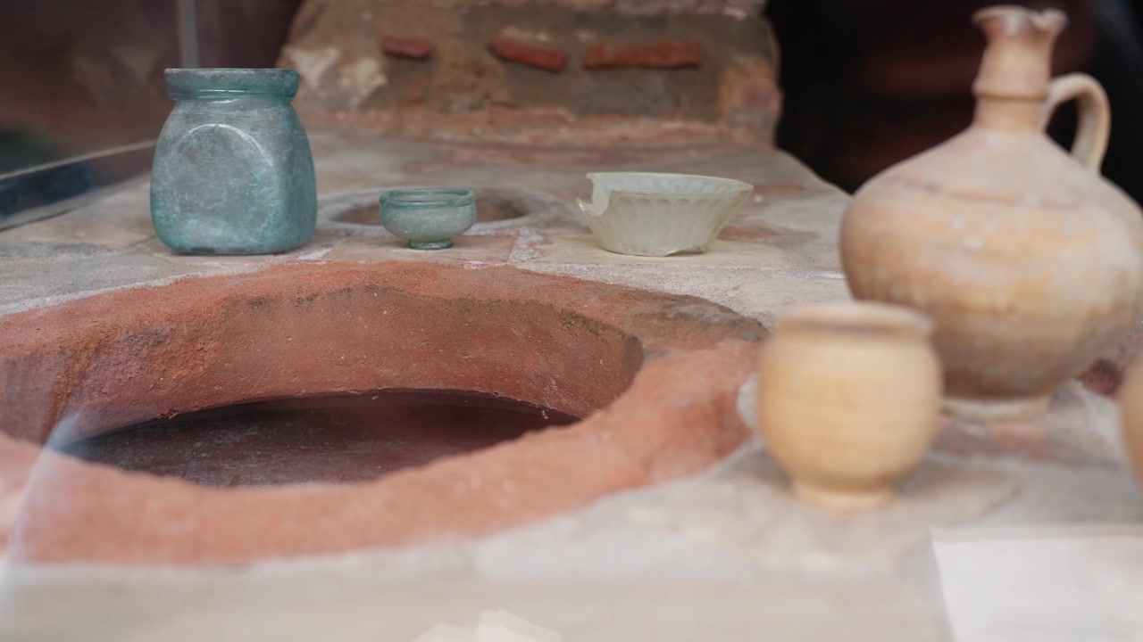 Piccoli vasi antichi esposti su un bancone di un termopolio di Pompei, con un'apertura circolare di dolium, vaso di vetro, ciotola e superficie conservata di un negozio di alimentari romano.