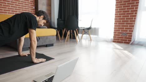 Young-man-doing-plank-exercise-with-online-tutorial-at-home