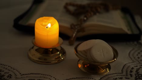 las hostias de la comunión en el crepúsculo iluminadas por la luz de un rosario de vela encendida