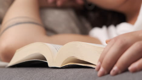close up of woman reading a book lying on the couch