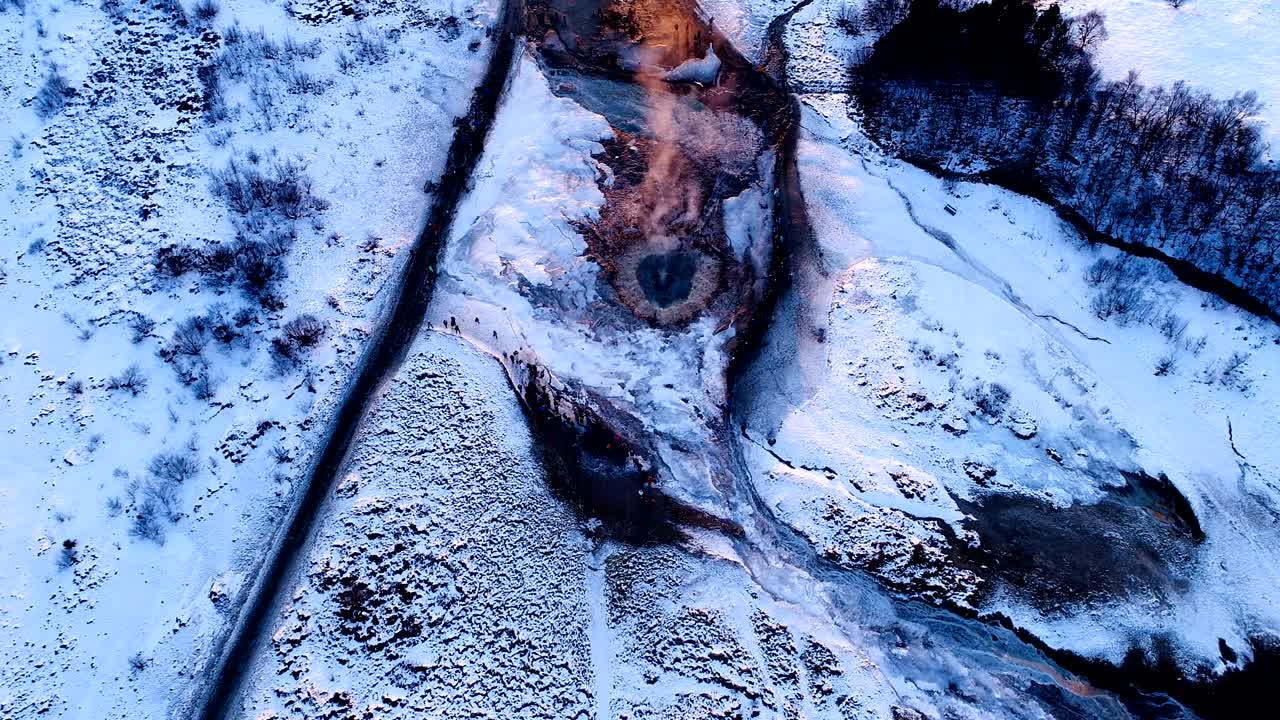 아이슬란드의 게이시르 (geysir) 의 중심에서 점점 더 멀어지는 드론의 아름다운 풍경. 흡연은 은 일몰 아래 게이저를 둘러싸고 산책하는 사람들과 함께 게이저에서 빠져나오고 있습니다.