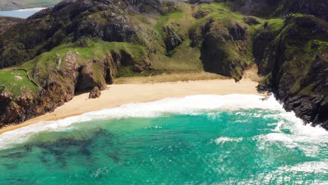 breathtaking aerial view of murder hole beach in ireland with clear water, cliffs, and visitors exploring the sandy shore
