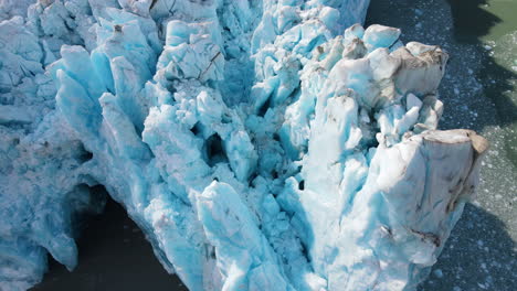 cinematic tilt-up drone view of the sharp ice ridges of dawes glacier, endicott arm fjord, alaska