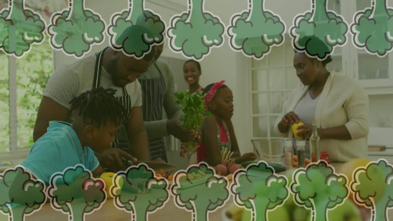 Animation of vegetables falling over african american family cooking together in the kitchen