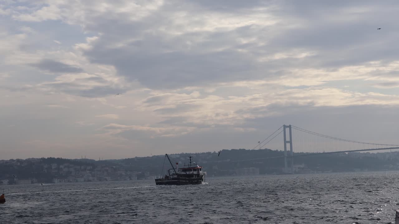Boat Cruising Near Bosphorus Bridge Which Connects Europe And Asia In Istanbul, Turkey - wide shot