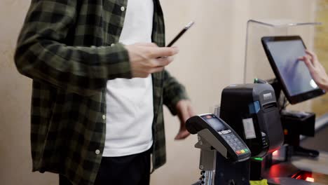 el cliente del mostrador de caja paga con el teléfono inteligente por sus alimentos