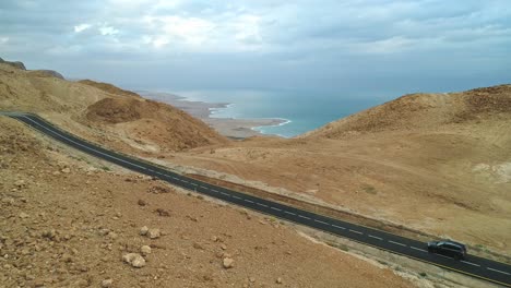 Aerial-footage-of-black-cars-driving-on-a-remote-desert-road