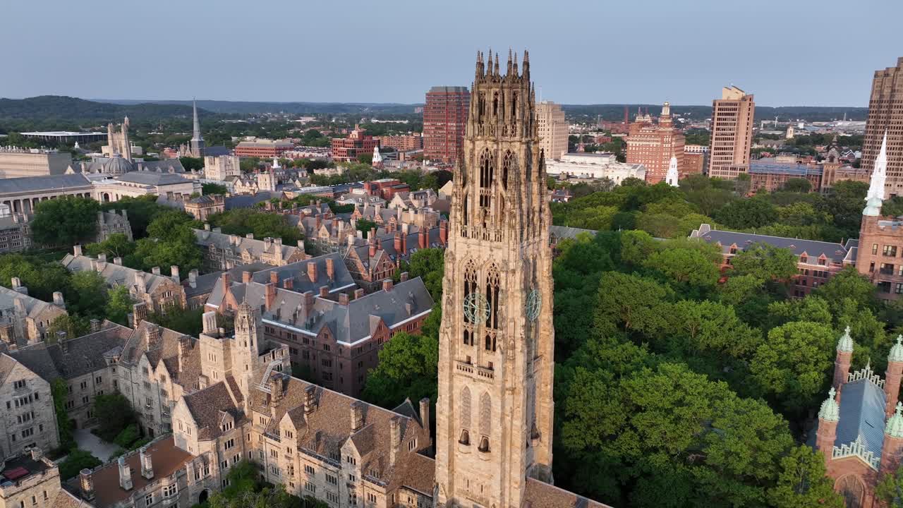 Harkness Tower at Yale old campus university of New Haven. American City in Connecticut at sunset. Summer day with green trees. Connecticut Financial Center In background. Aerial orbit wide shot
