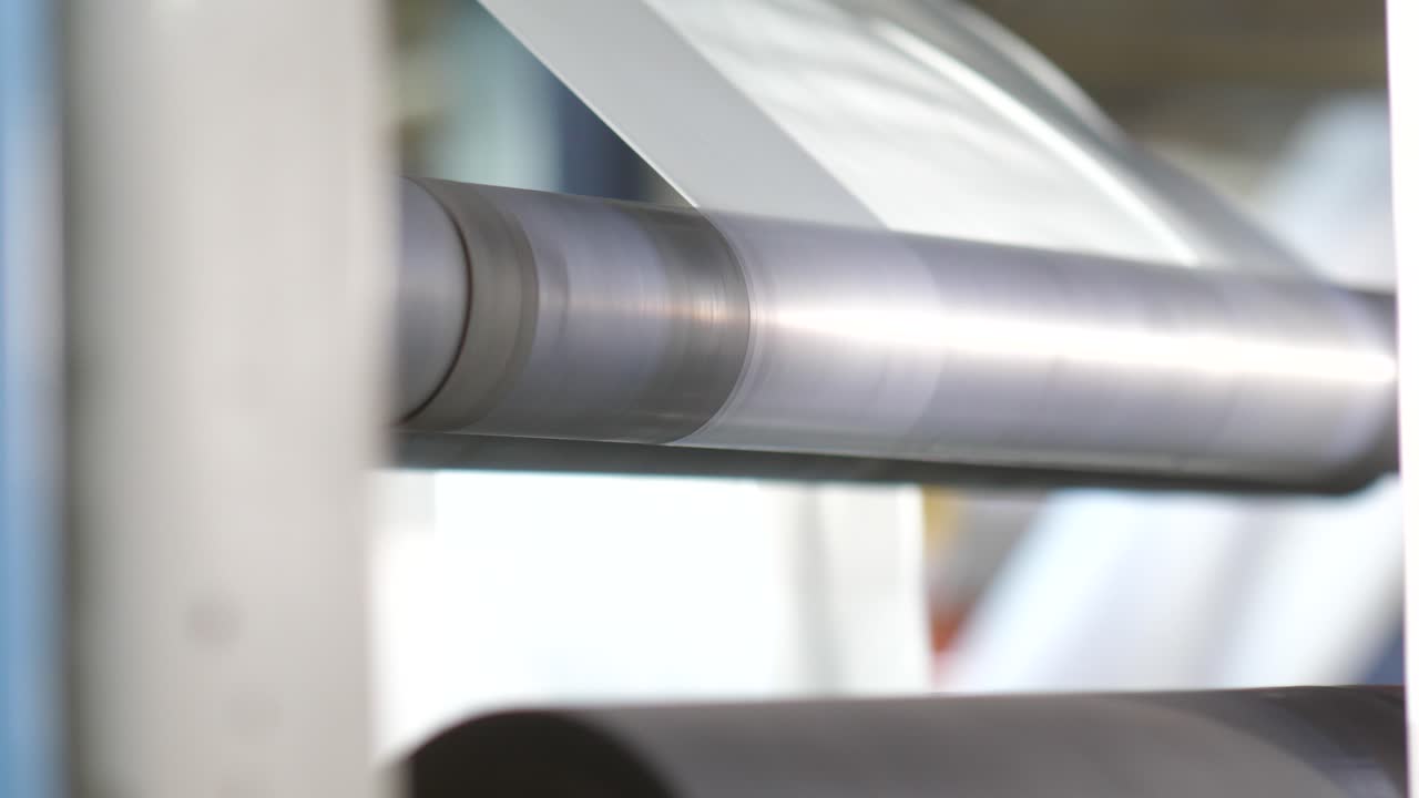 공장에서 롤러를 통과하는 플라스틱 셀로판 가방을 가까이서 볼 수 있습니다.