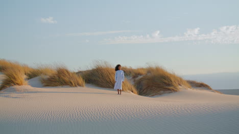 Lonely-woman-standing-desert-in-front-dry-grass-at-summer.-Girl-posing-on-nature