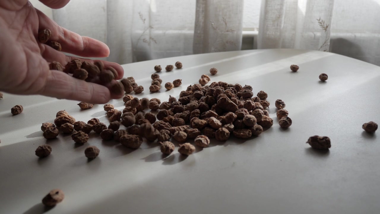 Mano sparge zigoli dolci essiccati su superficie bianca alla luce naturale della finestra