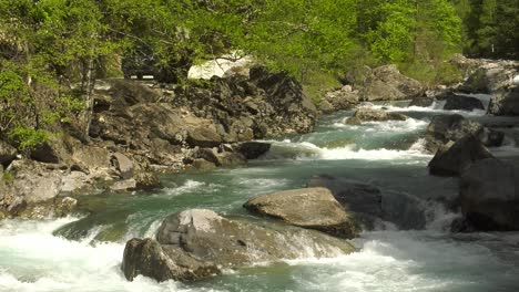 4x4-drives-by-rushing-mountain-river-in-forest,-Pyrenees-Spain