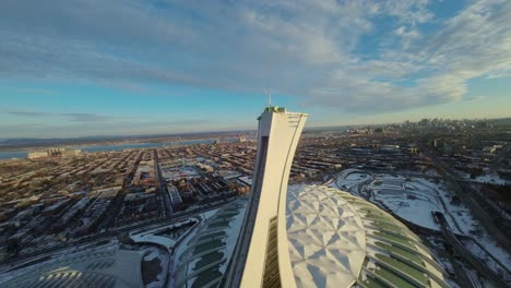 aerial fpv shot of olympic stadium with snowy rooftop at winter sunset