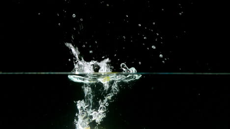 limón cayendo en el agua sobre un fondo negro