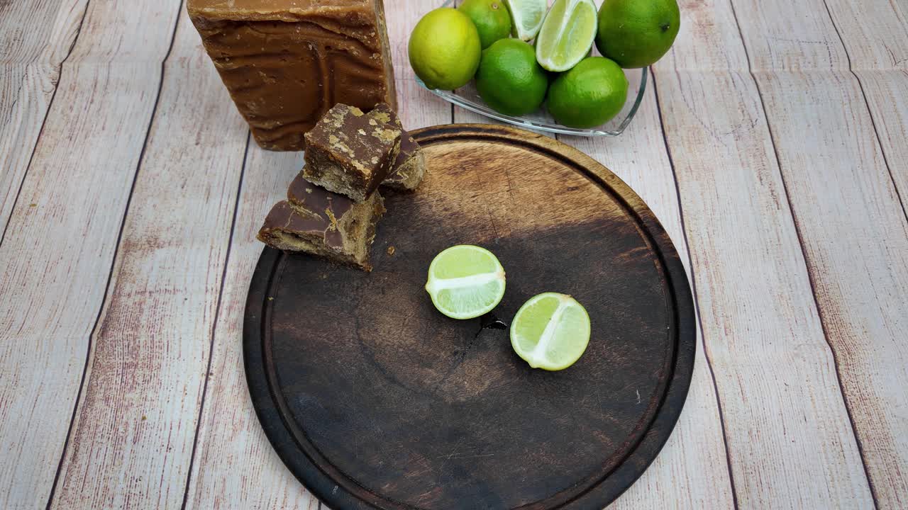 Primer plano de unas manos cortando limas frescas con esmero sobre una tabla de madera, lo que destaca el proceso de preparación de una bebida refrescante