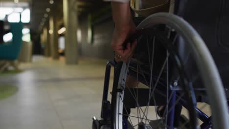 disabled african american businessman in wheelchair in office corridor