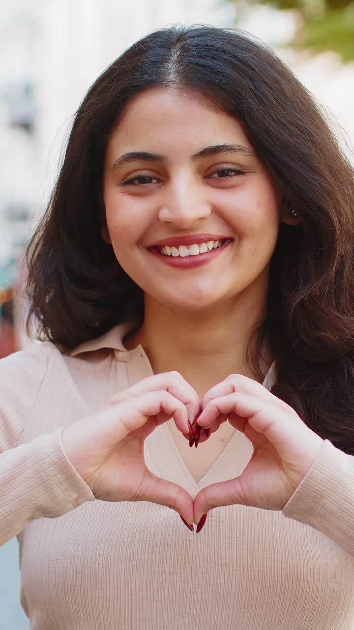 Indian woman makes symbol of love showing heart sign to camera express romantic positive feelings