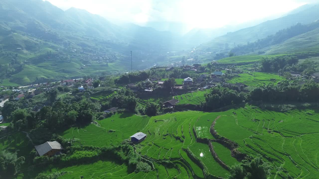 Drone slowly zooms out revealing terraced paddies and distant mountains beneath dramatic sky light