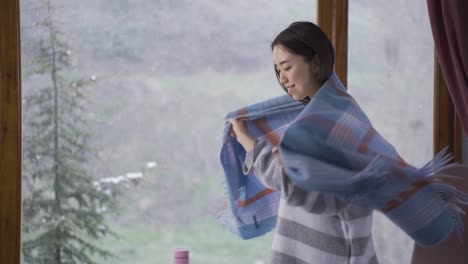 asian young woman watching snowfall through window.