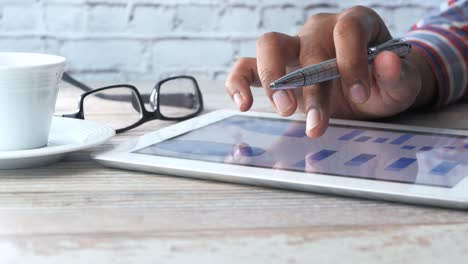 persona que utiliza una computadora tablet, examinando gráficos y gráficos