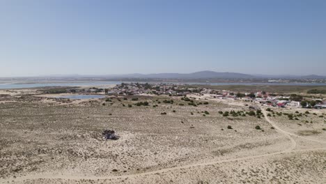 Isla-De-Armona,-Portugal,-Mostrando-Un-Pequeño-Pueblo-Costero-Rodeado-De-Terreno-Arenoso,-Vista-Aérea