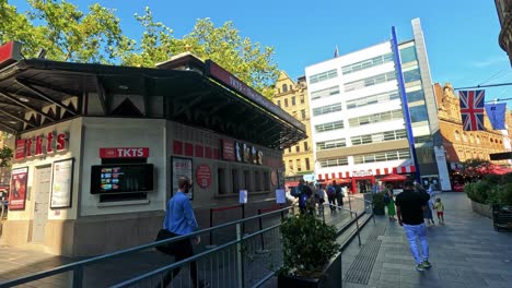 pedestrians pass by a theatre ticket booth