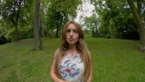 pretty woman stands in the green city park in summer