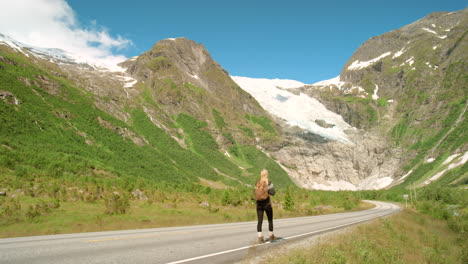 woman hiking along a scenic roadway in norway's mountains near a glacier