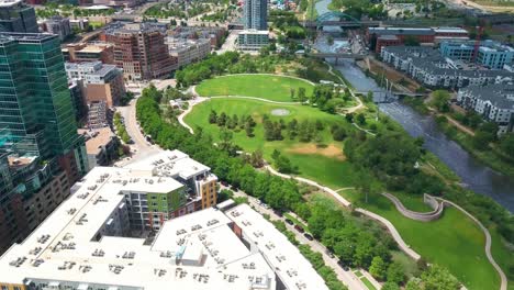 aerial drone shot tilting up from green urban park to reveal denver suburbs with mile high stadium