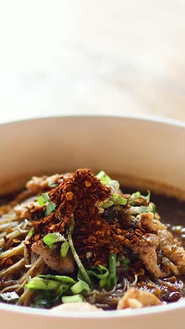 adding ingredients to a bowl of noodle soup