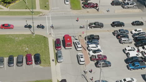 Aerial-View-Of-Red-Ambulance-Vehicle-Driving-And-Turning-On-The-Intersection-During-The-Dogwood-Festival-In-Siloam-Springs,-Arkansas