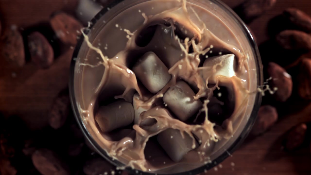 Marshmallow in movimento rallentato che si tuffano nella cioccolata calda